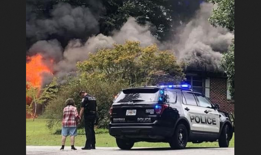 Sem perceber, agente é fotografado orando com mulher que perdeu casa em incêndio. (Foto: Reprodução / Facebook)