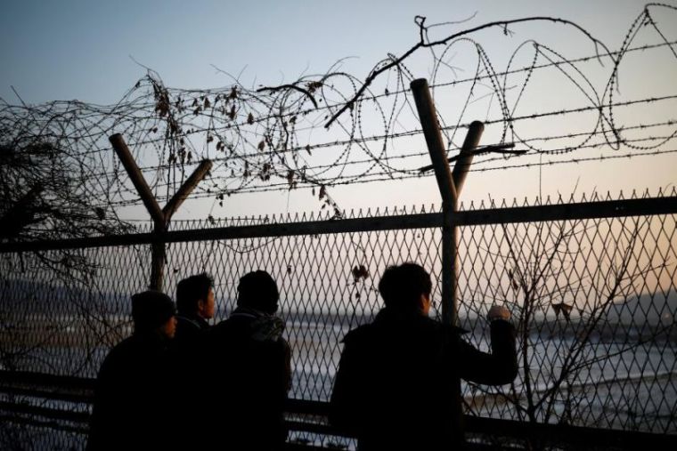Pessoas olham para o norte através de uma cerca de arame farpado perto da zona militarizada que separa as duas Coreias, em Paju, Coreia do Sul.