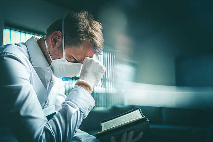 Médico a ler a Bíblia e a orar
